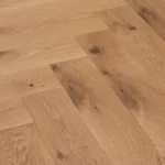 Light oak herringbone wood flooring with natural grain and knots