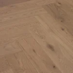 Light oak herringbone wood flooring with visible knots and grain