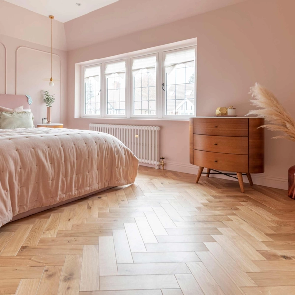 Pink bedroom with wood herringbone floor.